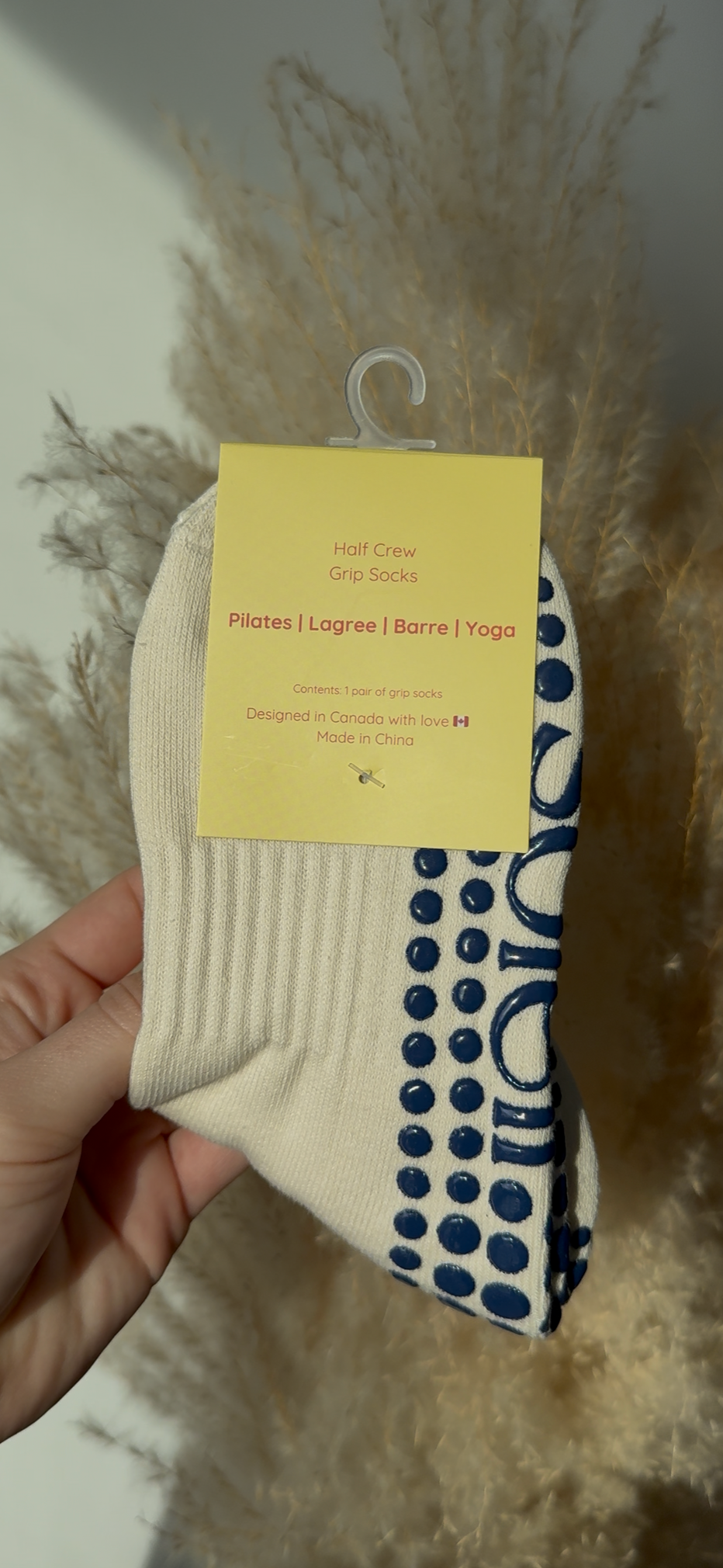 Beige sock with blue grips held by a hand against a neutral background