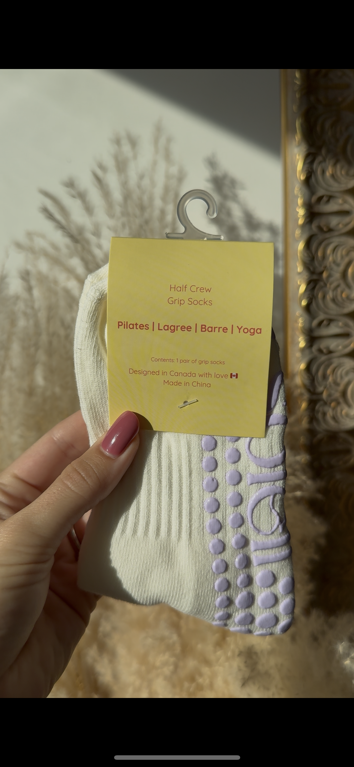 White sock with purple sole held by a hand against a textured wall background