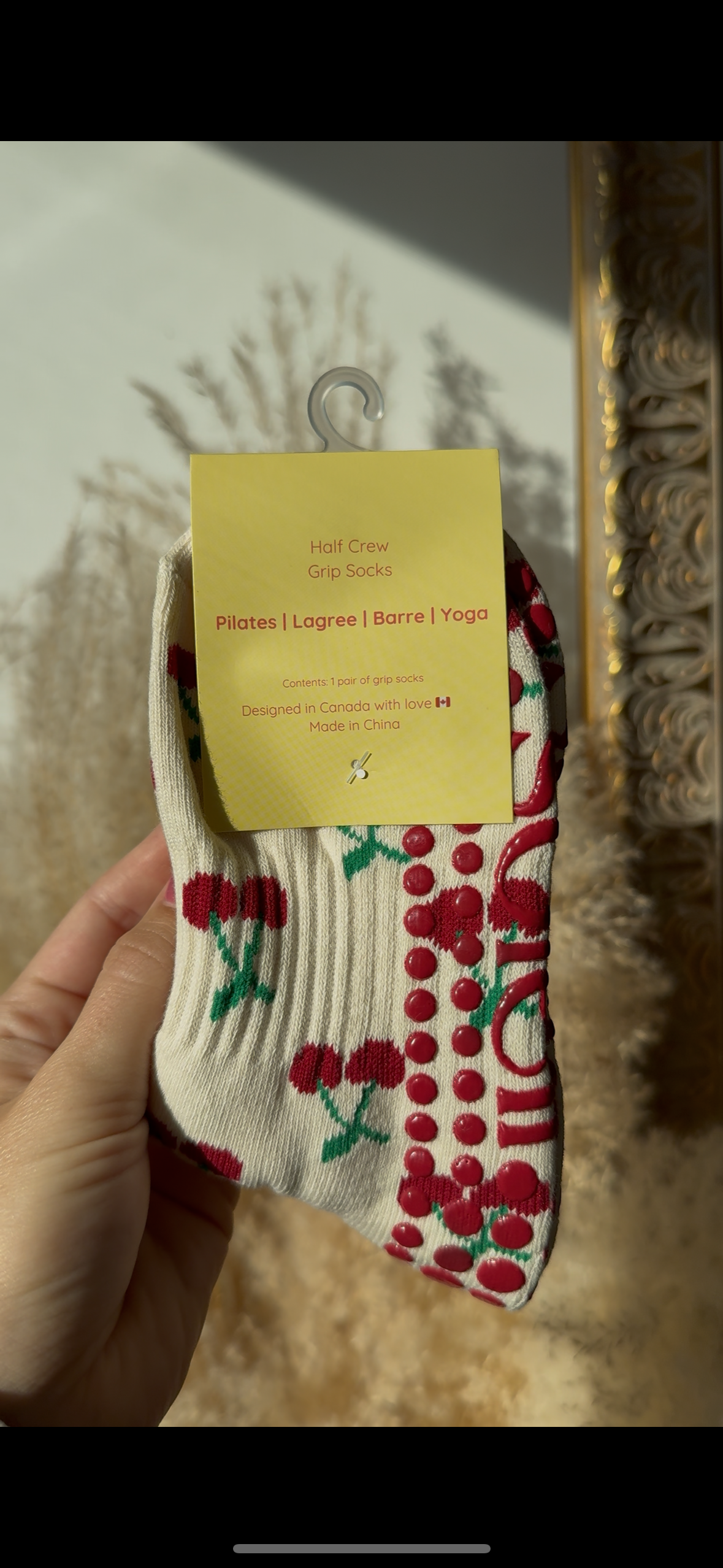 Sock with cherry design held by a hand against a decorative mirror background